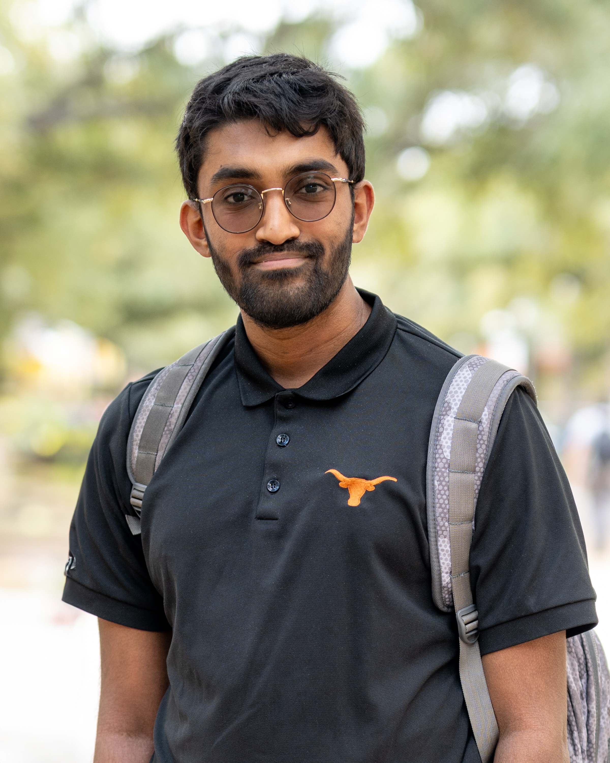 A bearded young man wears a backpack and polo shirt with the longhorn silhouette.